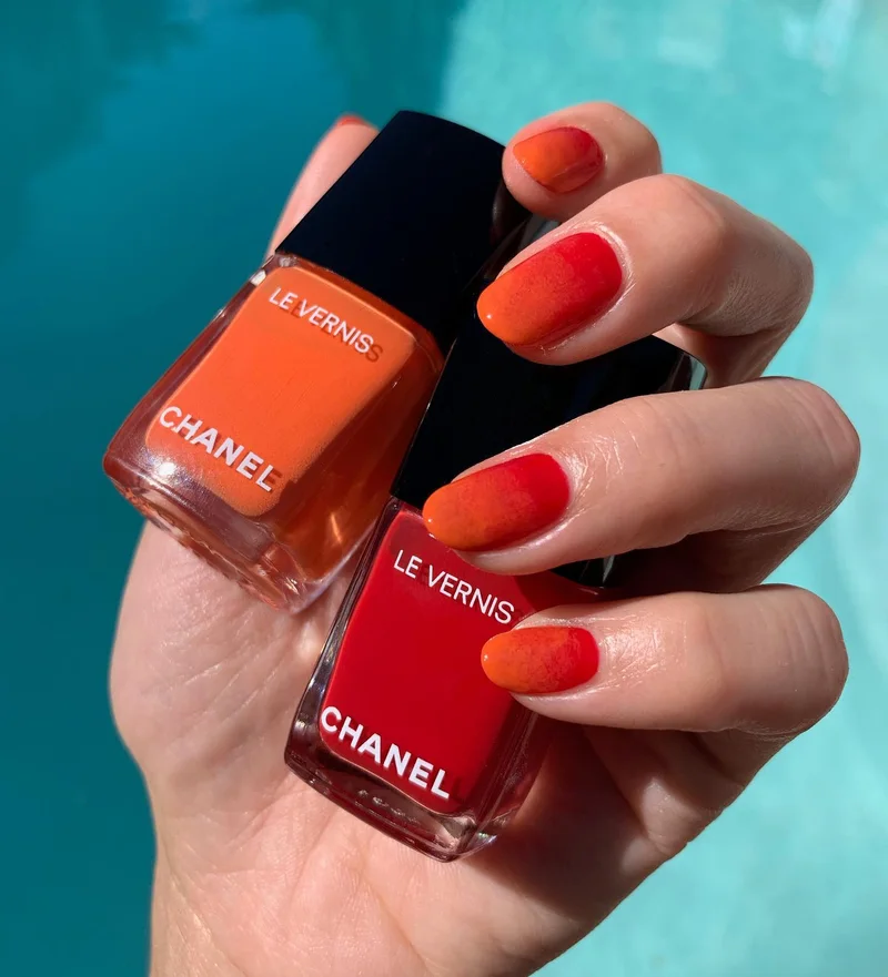 Нігті з помаранчево-червоним градієнтом і флаконами лаку