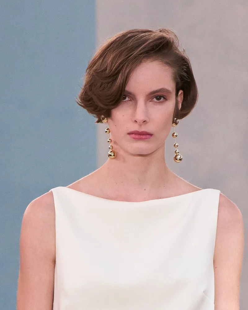 Модель Carolina Herrera осінь-зима 2026/27 з короткою ретро-хвилею і довгими сережками